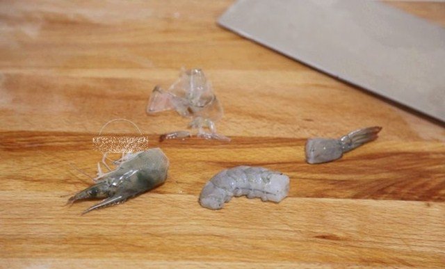 Cắt rời đầu và đuôi tôm như hình. Phần giữa con tôm thì bóc bỏ vỏ.